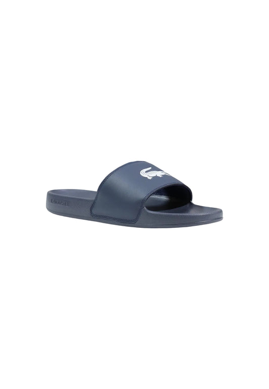 Ciabatte blu a fascia da uomo Lacoste Serve Slide 1.0 con logo del coccodrillo in rilievo sulla fascia ampia e suola ergonomica coordinata. Vista laterale