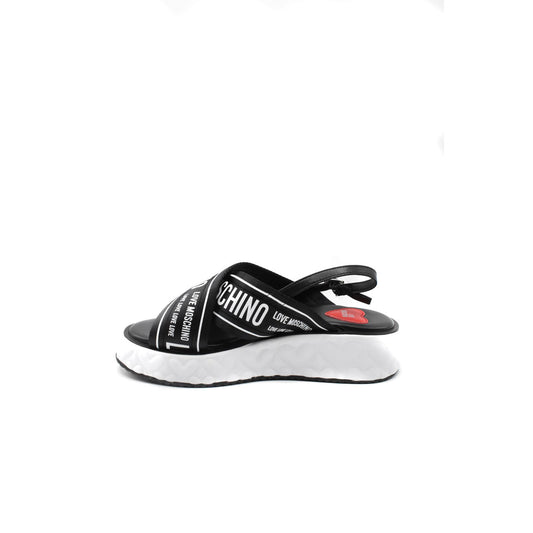Sandali Love Moschino donna neri in pelle modello B_44919. Sandalo estivo basso in vera pelle nera con suola in gomma confortevole, calzatura flat di marca comoda ed elegante per la stagione calda.