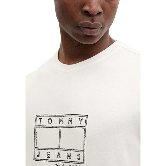 T-shirt Tommy Jeans Stamp; 100% Cotone. Logo effetto timbro sul petto, vestibilità regular, branding ricamato sulla manica. Maglia uomo in jersey morbido dal look vintage-contemporaneo. Colore bianco vista frontale Dettaglio logo