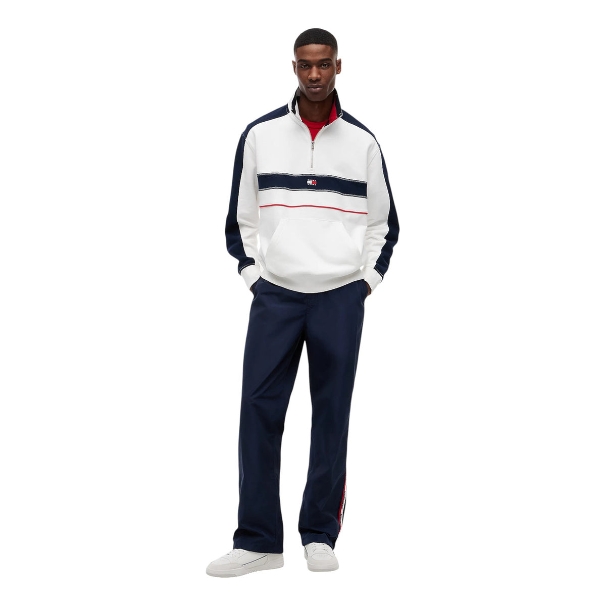 Felpa Uomo Tommy Jeans; Bianco e Multicolore. Tessuto in spugna di cotone organico, taglio relaxed fit con spalle scese, collo a imbuto con mezza zip e tasca a marsupio. Logo badge frontale, stile street-wear 4 stagioni. Figura intera