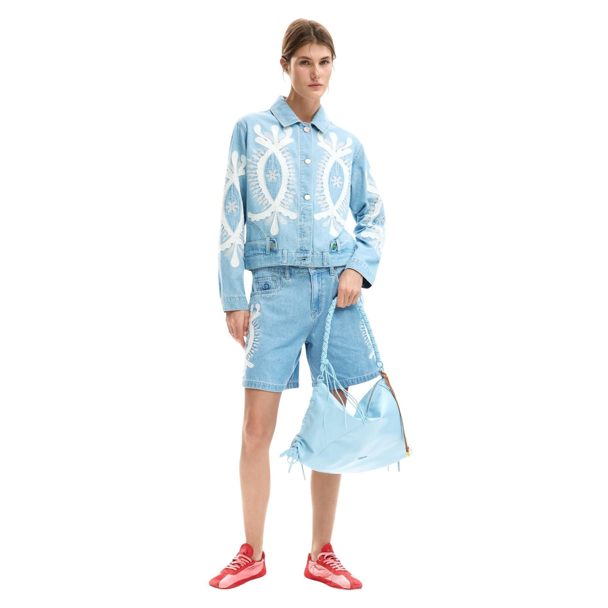 Giacca di jeans in cotone 100% con ricami in tonalità blu e design a taglio regular. Colletto a camicia e maniche lunghe con chiusura con bottone ai polsini. Chiusura frontale con bottoni e cuciture visibili. Indossata da modella vista frontale Figura intera