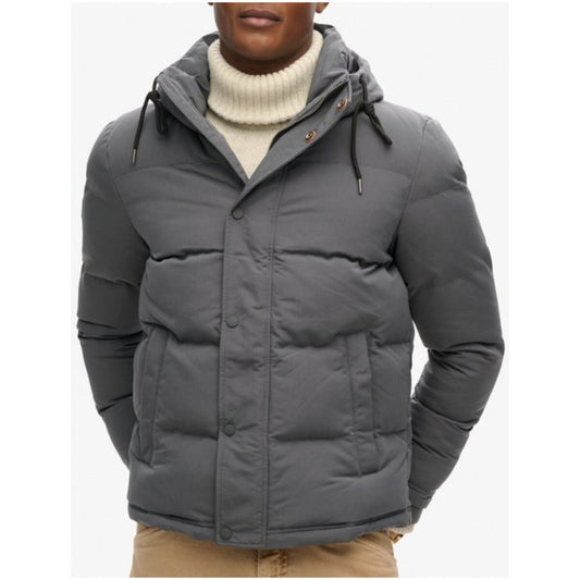 Superdry Everest Short Puffer; 100% materiali riciclati, trattamento idrorepellente, cappuccio imbottito. Calore estremo e vestibilità perfetta per l'inverno. Vista frontale indossato colore grigio