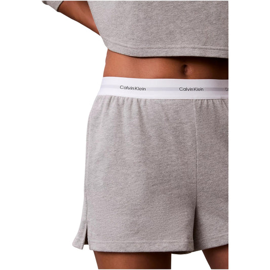 Pantaloncini pigiama Calvin Klein donna grigi. Shorts da notte e loungewear in morbido jersey di cotone a tinta unita con tasche laterali e spacco sull'orlo, caratterizzati dalla classica fascia elastica logata in vita, stile sportivo e minimalista.