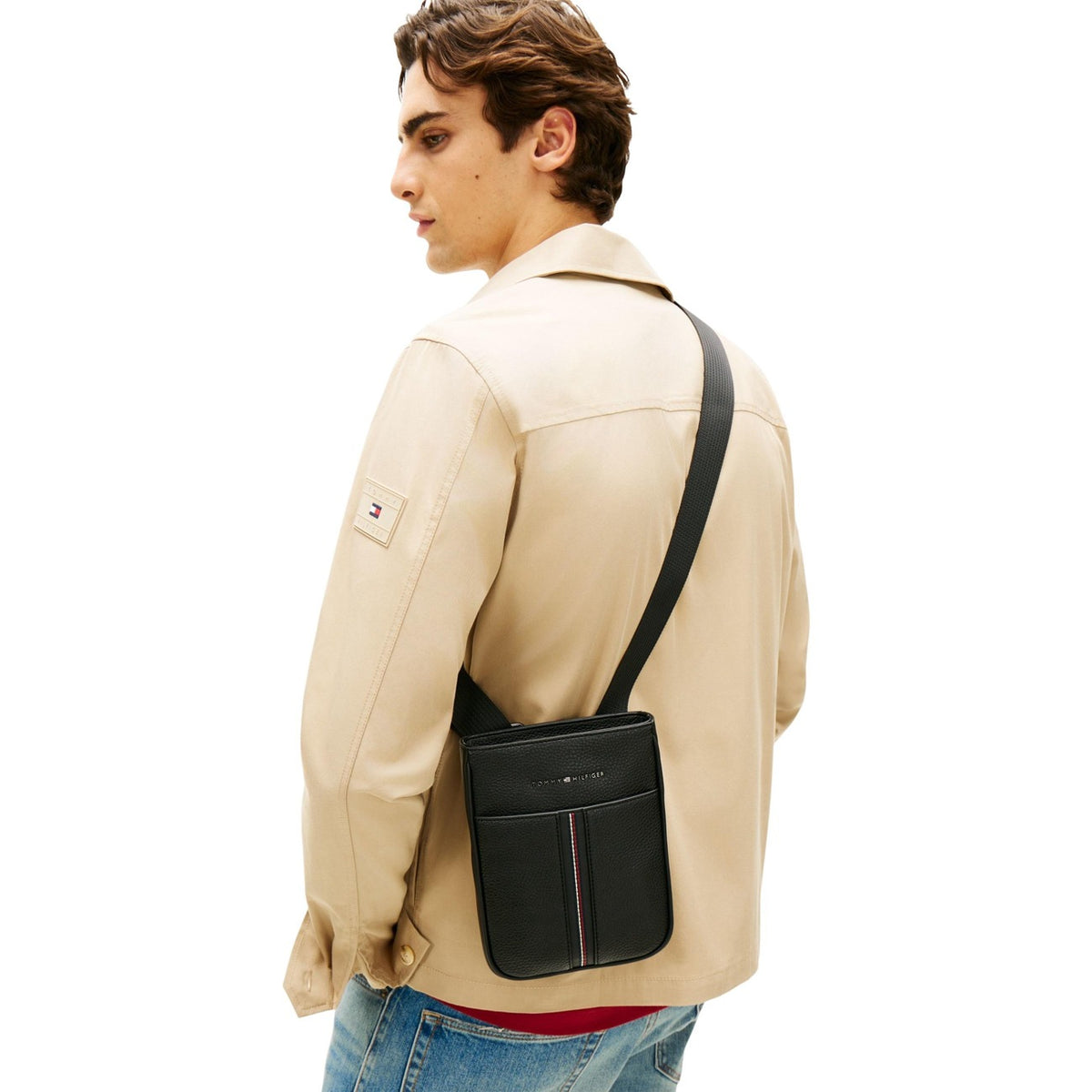 Tracolla Tommy Hilfiger zigrinata; chiusura con zip, scomparto unico, logo metallico. Finitura resistente, tracolla regolabile, stile urban-chic. Indossato da modello
