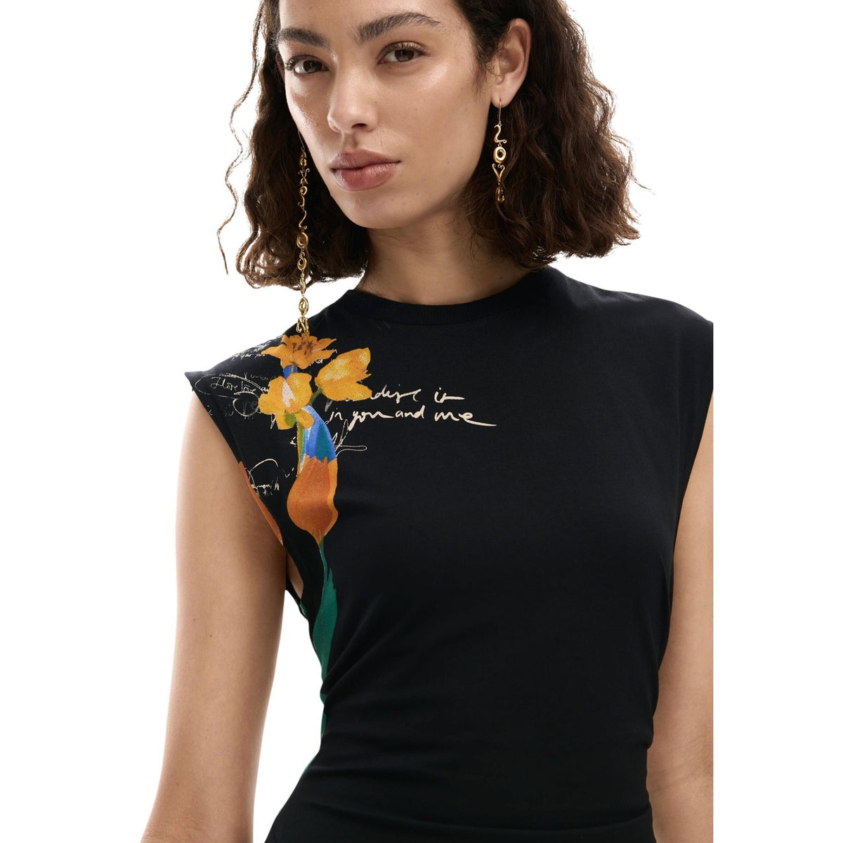Abito senza maniche, dal taglio asimmetrico, con drappeggio sul fianco e stampa posizionata di fiori sul fianco e sull’orlo.
Vista frontale indossato da modella dettaglio scollo