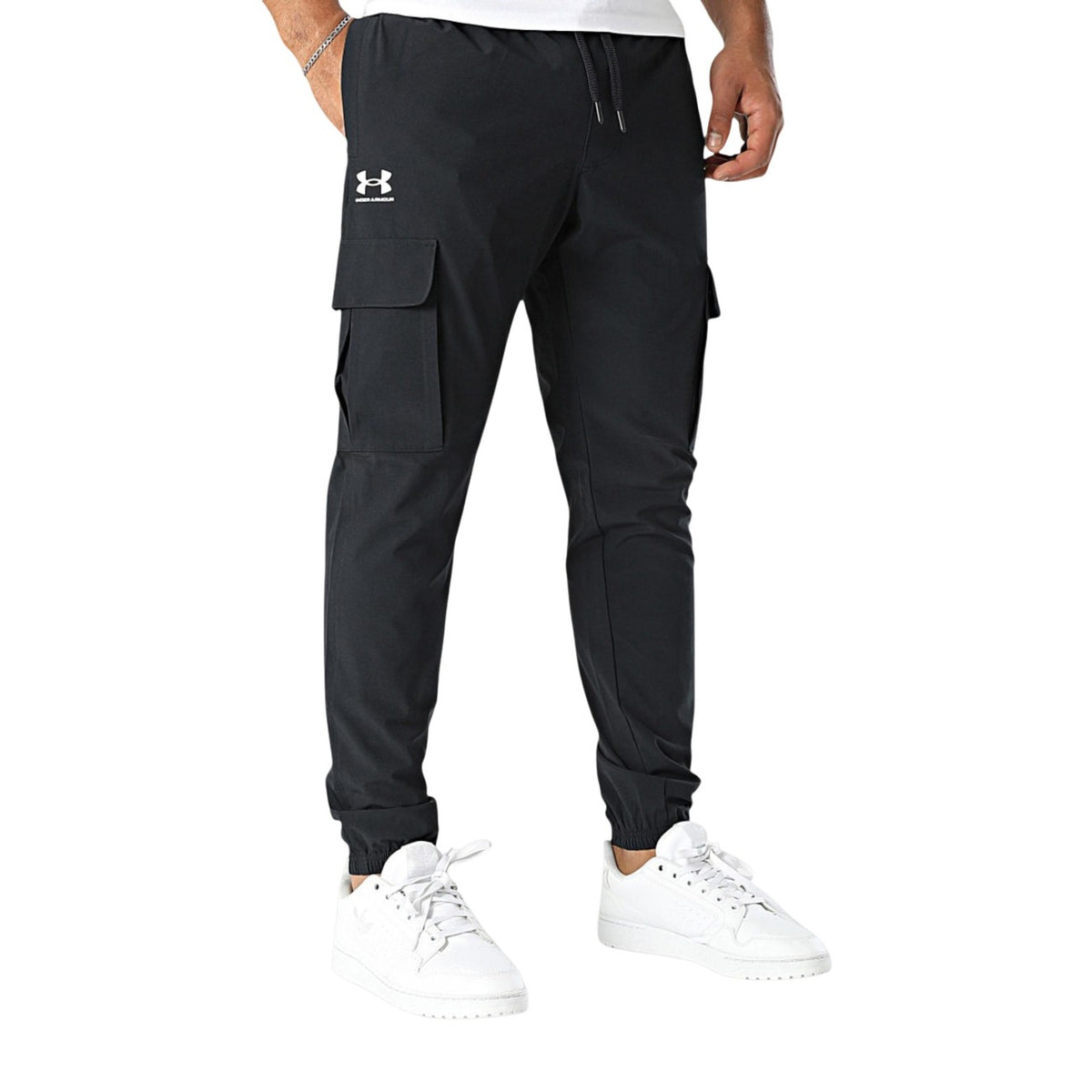 Under Armour Vibe Woven Cargo; pantalone nero tecnico multitasche in poliestere stretch, fondo con elastico e massima libertà di movimento per lo sport e il tempo libero. Vista laterale