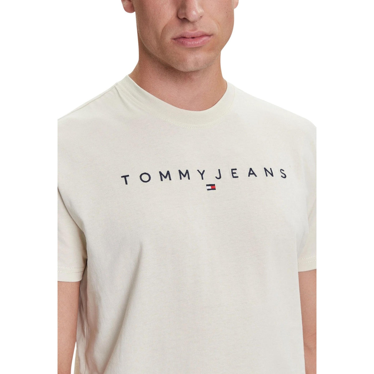 T-shirt Tommy Hilfiger Jeans LINEAR LOGO TEE uomo beige chiaro maniche corte scollo tondo 100% cotone organico - vista logo in primo piano frontale indossata da modello
