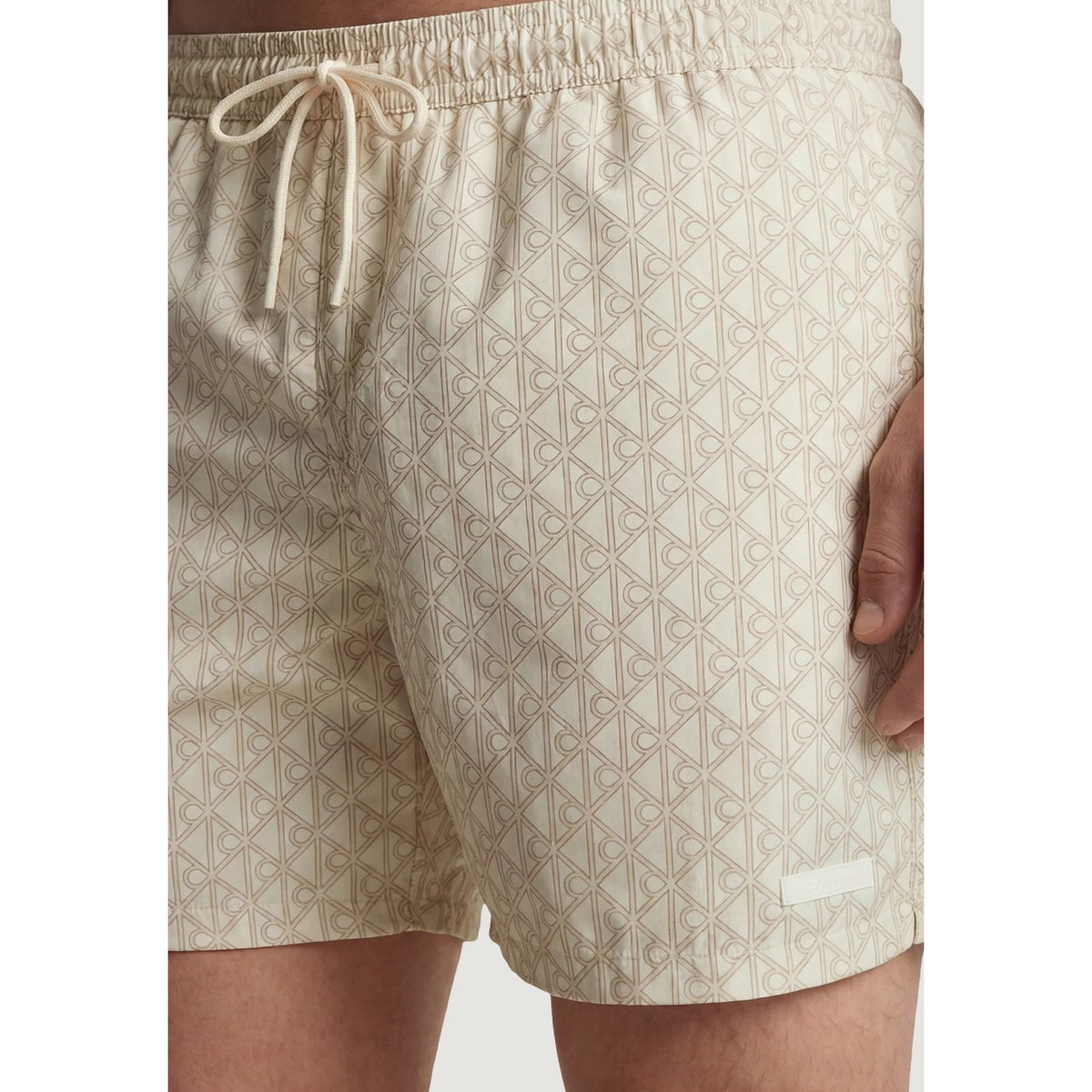 Boxer Mare Calvin Klein; Beige. 100% Poliestere Riciclato. Vita regular con coulisse, lunghezza media, asciugatura rapida. Logo minimal, stile casual e sostenibile. Dettaglio stampa