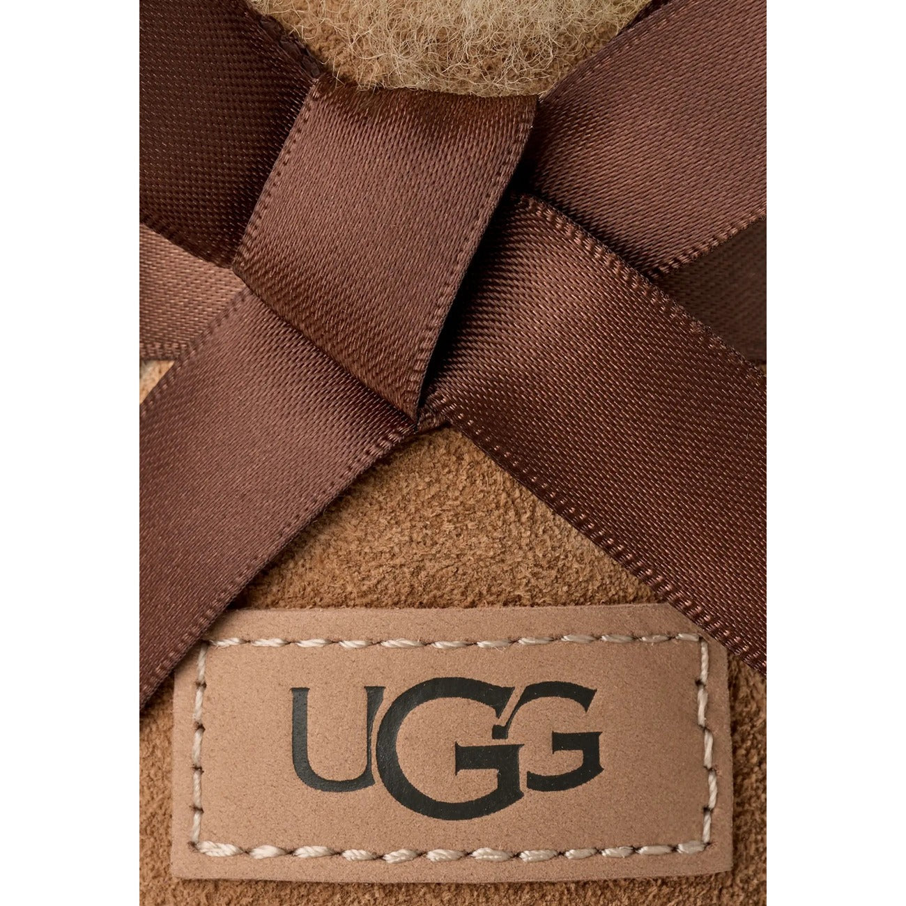 UGG Ultra Mini Bailey Bow donna Chestnut 1185491. Stivaletti bassi in pelle scamosciata beige foderati in caldo montone con fiocco in raso posteriore, suola leggera in EVA e trattamento idrorepellente.