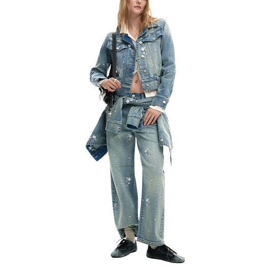 Giacca di jeans stile trucker, con colletto a revers, elastico in vita e piccoli dettagli ricamati. Vista frontale figura intera indossata da modella