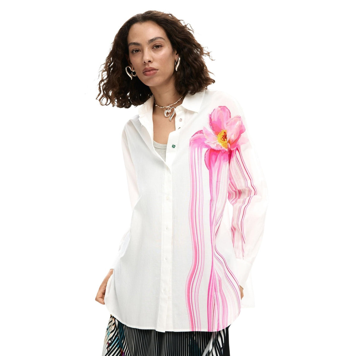 Camicia dal taglio oversize in tinta unita con grande fiore stampato, linee colorate che scendono lateralmente e bottoni stampati.
Vista frontale indossata da modella