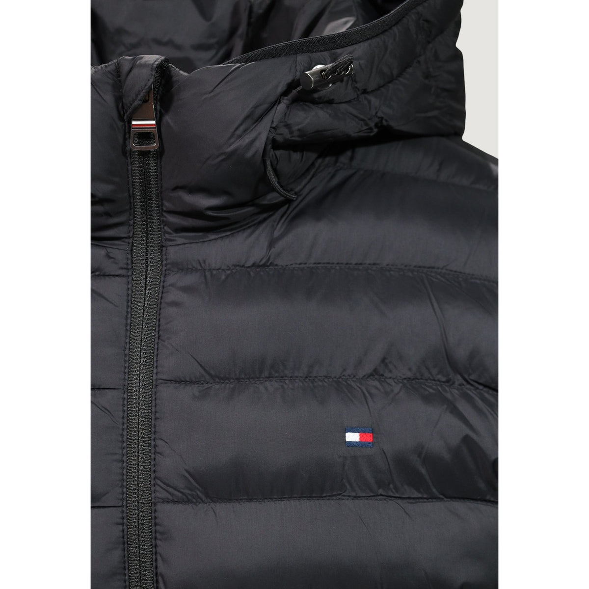 Piumino Tommy Hilfiger uomo nero MW0MW43464. Giacca imbottita trapuntata con cappuccio, 100% poliestere leggero e termico, vestibilità regolare, cerniera zip e tasche laterali con zip.