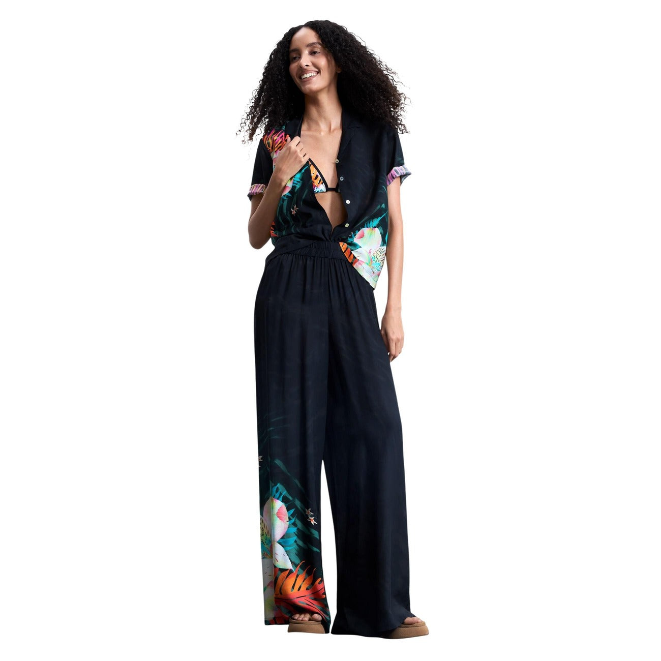 Pantaloni palazzo Desigual DAIKIRI; 100% viscosa. Vita elastica, stampa floreale fondo gamba, vestibilità ampia. Pantaloni estivi donna ultra-leggeri, freschi e traspiranti. Figura intera