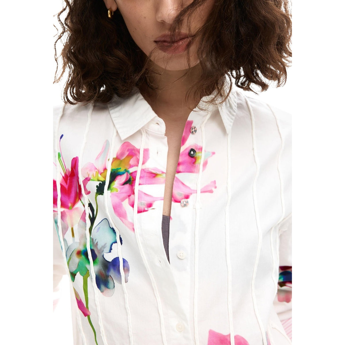design presenta una raffinata lavorazione a righe verticali in rilievo che valorizza la silhouette, mentre la stampa floreale vivace aggiunge un tocco femminile e originale. Il colletto classico e la chiusura frontale con bottoni rendono questa camicia versatile