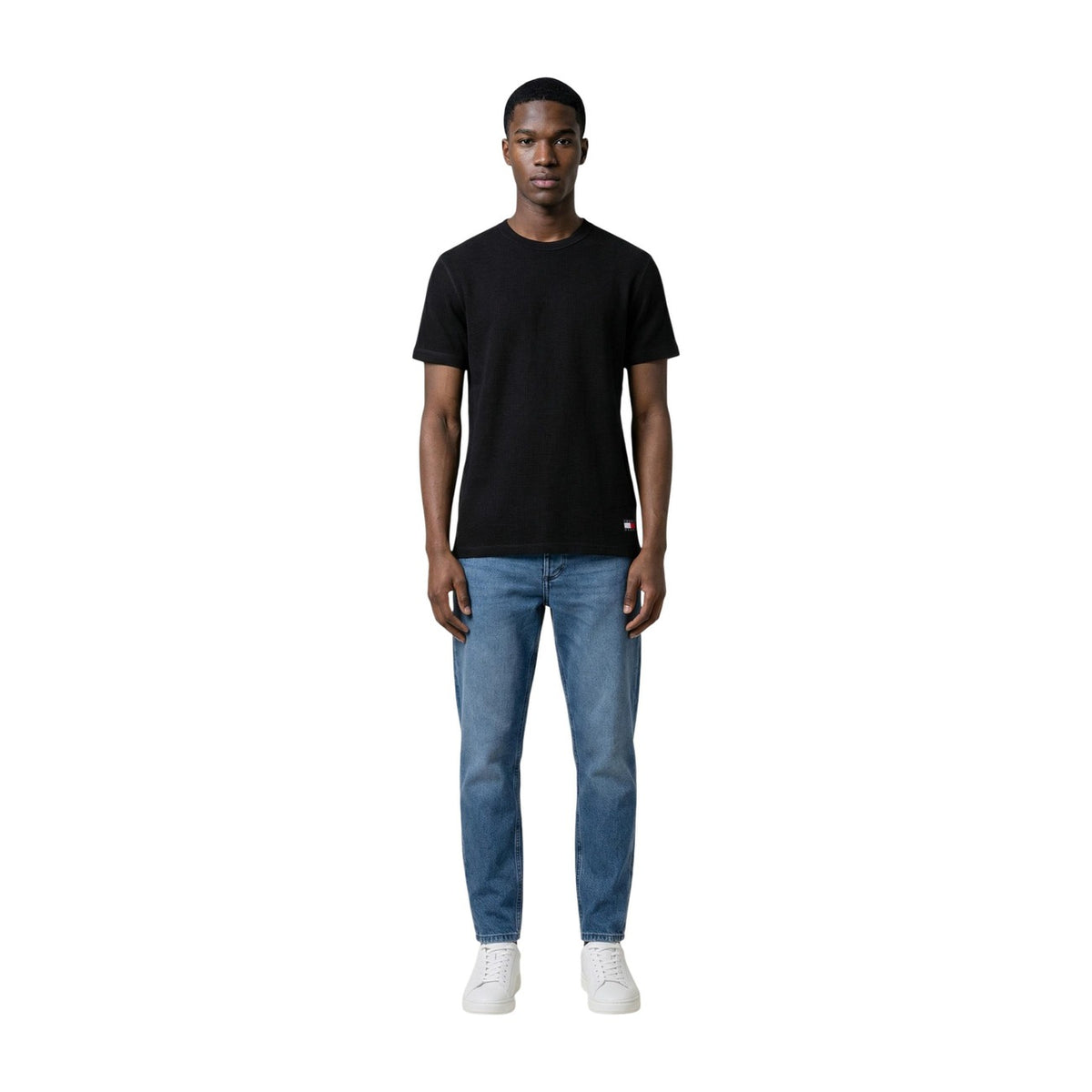 Tommy Hilfiger Jeans T-Shirt nera REGULAR FIT maniche corte Uomo. Realizzata 60% cotone organico e 40% poliestere. Vista frontale Figura intera indossato da modello