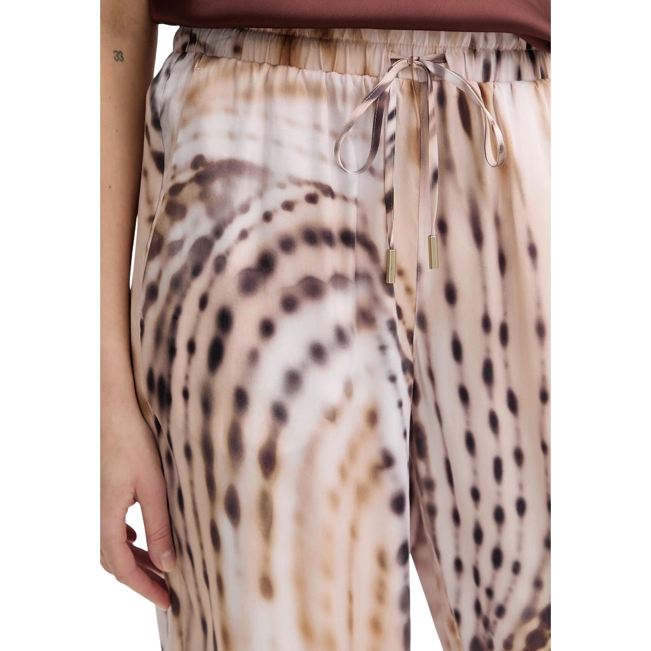 Pantaloni palazzo Guess donna rosa modello W6GB07 W1781. Pantaloni ampi stile jogger fluido in tessuto leggero rosa con motivo geometrico a onde, vita elastica con lacci e tasche a filo, pantalone casual chic a gamba larga per la mezza stagione.