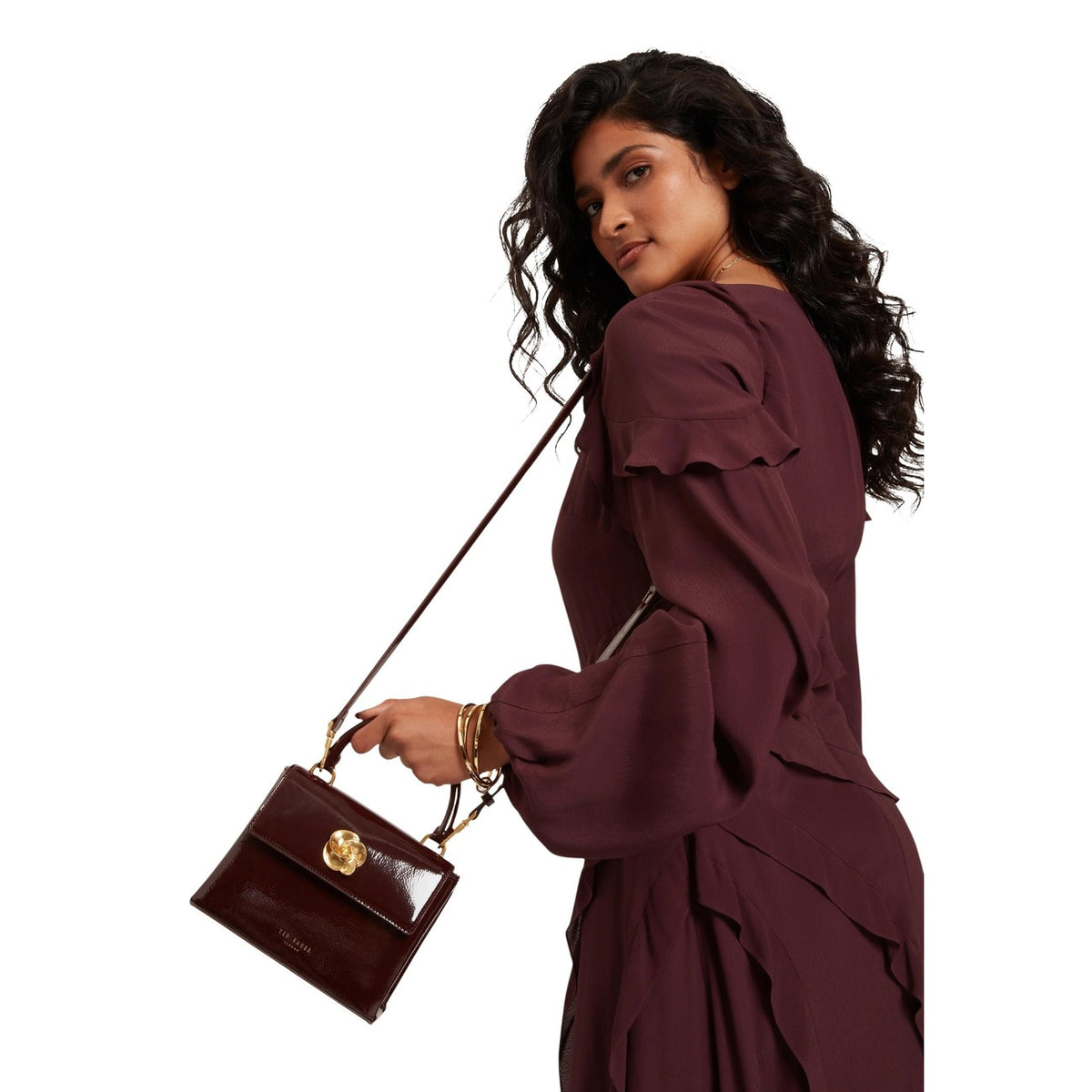 Ted Baker Rose Detail Mini Bag; borsa compatta effetto crinkle con chiusura a rosa gold. Realizzata in materiali riciclati, elegante e versatile per occasioni speciali. Vista frontale con tracolla indossata da modella