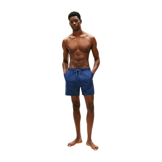 Costume Shorts Tommy Hilfiger; Righe Ithaca tono su tono. Tessuto tecnico, tasca con zip laterale, dettagli iconici sul retro. Lunghezza media, stile nautico elegante e funzionale. Figura intera
