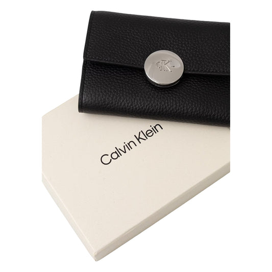 Portafoglio Compatto Donna Calvin Klein Trifold; Nero. 100% Vera pelle martellata, chiusura con automatico logato, scomparti interni per carte, banconote e portamonete zippato. Dimensioni micro (6x9 cm), stile elegante 4 stagioni. Vista con scatola 