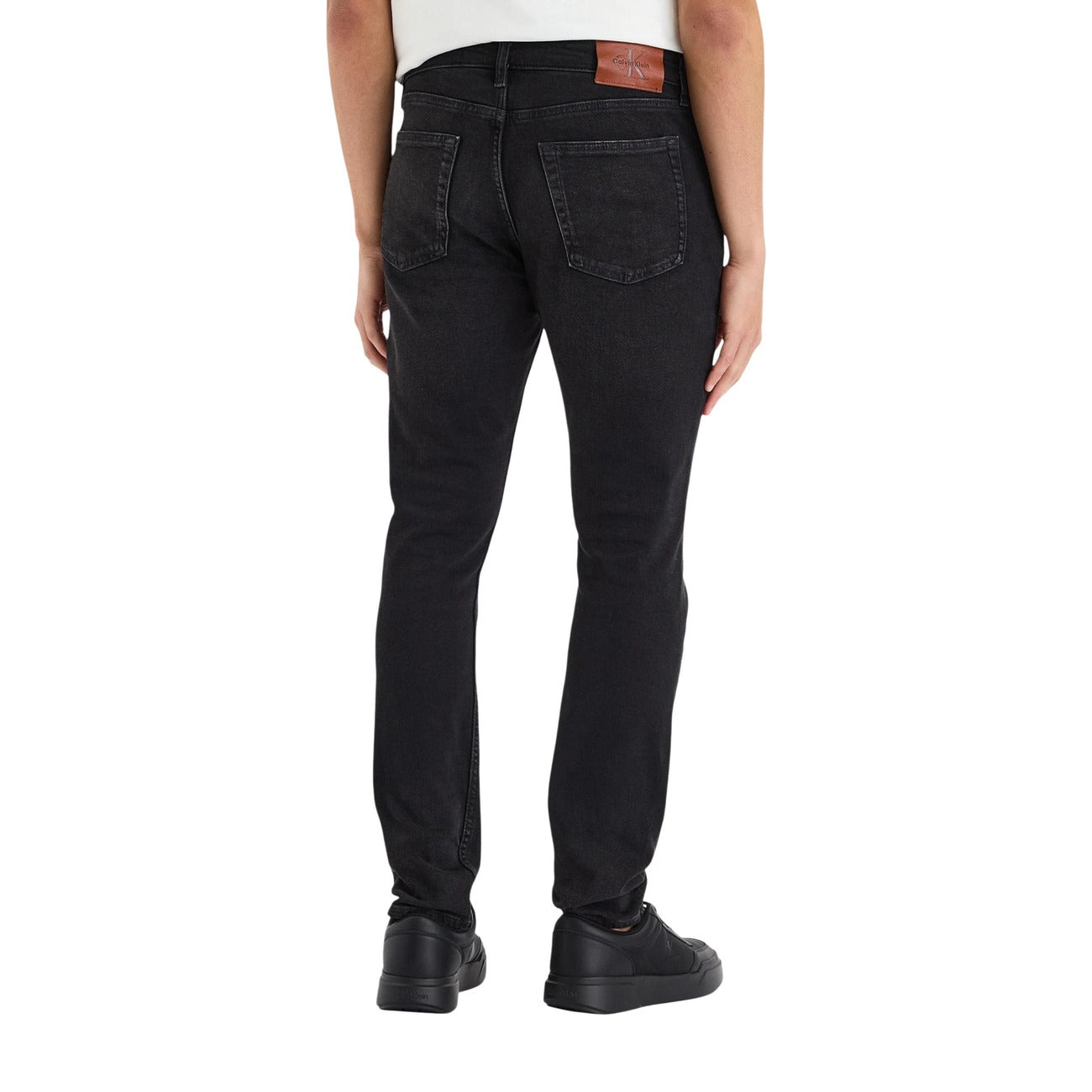 Jeans Slim Neri Calvin Klein; Cotone Stretch. Taglio 5 tasche, vita regular, chiusura con zip. Patch logo in pelle, vestibilità aderente e confortevole. Il classico denim nero rivisitato. Vista posteriore 