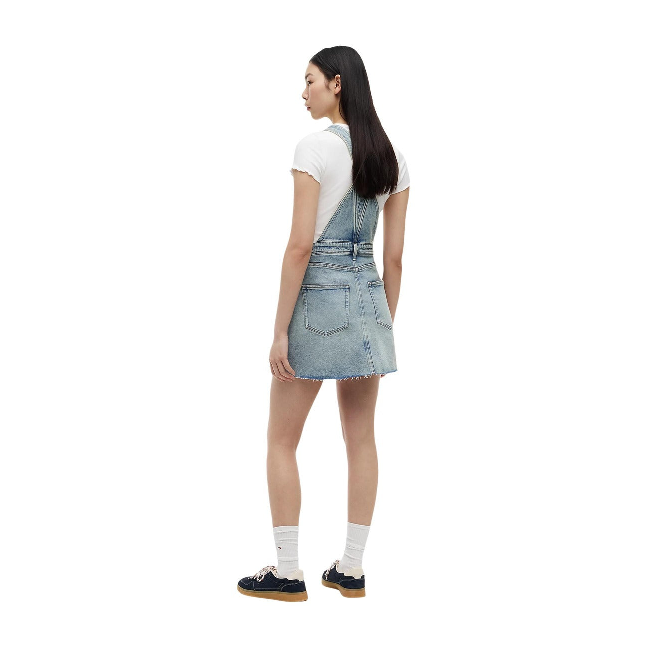 Abito salopette jeans Tommy Jeans donna modello DW0DW228741AB. Vestito corto in denim chiaro regular fit a cinque tasche con bretelle e bottoni metallici, tasca sul petto con mini bandiera logo Tommy, stile casual e streetwear in cotone biologico.