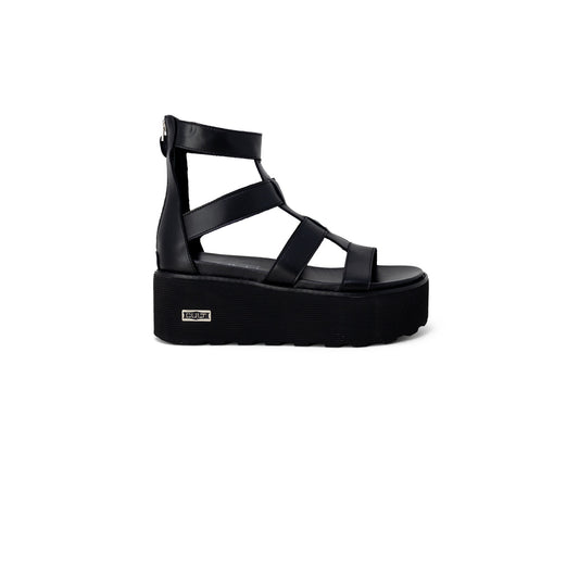 Sandali Platform Cult Nancy; Nero. Pelle e poliuretano, tacco 6 cm, suola dentellata. Chiusura con zip posteriore, logo metallico laterale. Stile grintoso e moderno. Vista laterale 