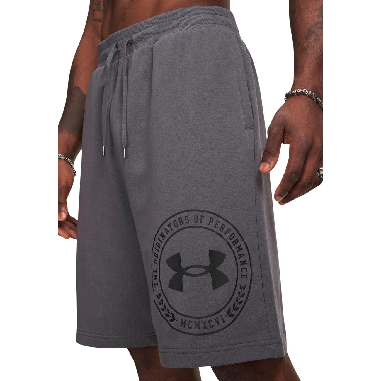 Bermuda Uomo Grigi Under Armour Sportivi; Pantaloncino in spugna leggera misto cotone con stampa logo laterale. Vita elastica, tasche laterali e tasca posteriore, stile activewear e tempo libero.