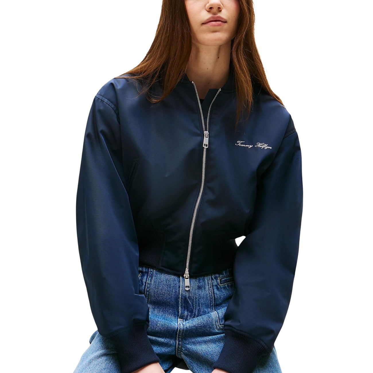 Bomber Crop Tommy Hilfiger; Blu Navy. Tessuto idrorepellente, imbottitura termica, fit rilassato. Dettagli a coste, chiusura con zip e logo ricamato. Giacca corta funzionale e di tendenza. Vista frontale 