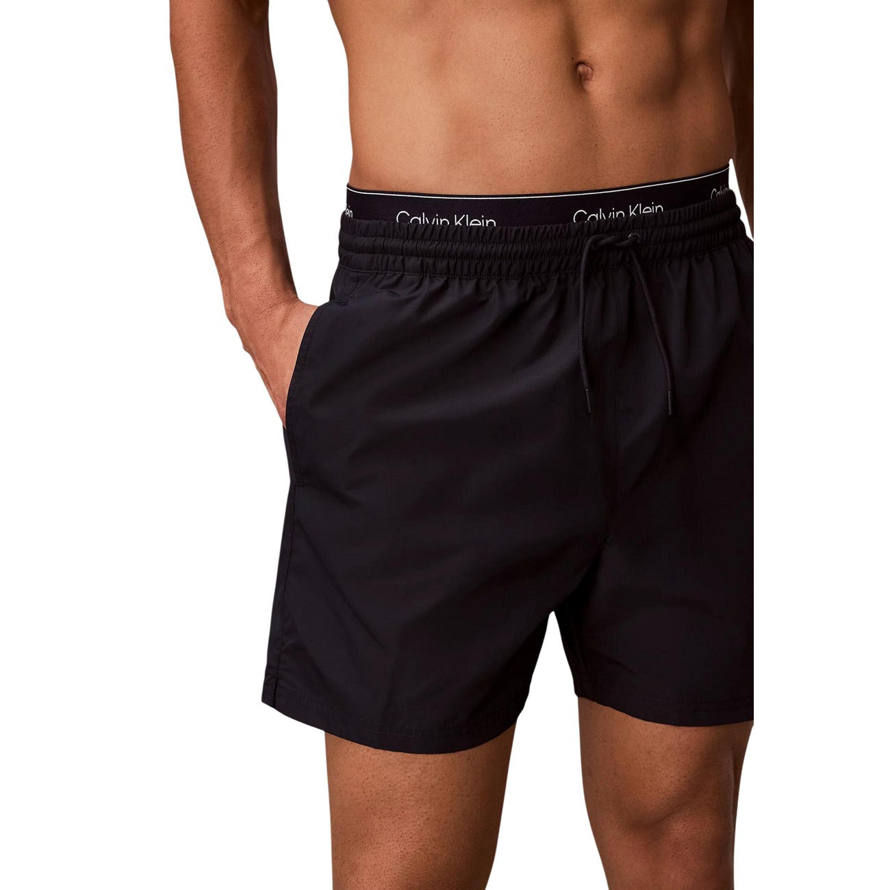 Boxer Mare CK Essentials; Tessuto Impermeabile. Doppia vita elastica logata, asciugatura rapida, lunghezza media. Tasca con velcro, slip a rete interno. Stile minimalista e funzionale per l'estate.
