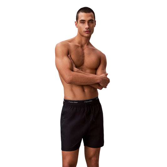 Boxer Mare CK Essentials; Tessuto Impermeabile. Doppia vita elastica logata, asciugatura rapida, lunghezza media. Tasca con velcro, slip a rete interno. Stile minimalista e funzionale per l'estate. Vista frontale 
