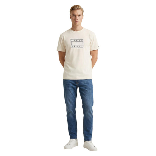 T-shirt Tommy Jeans Bianca; 100% Cotone Rigenerato. Regular fit, logo grafico stampato, scollatura tonda a costine. Capo versatile 4 stagioni, ideale per outfit casual e urban. Figura intera 