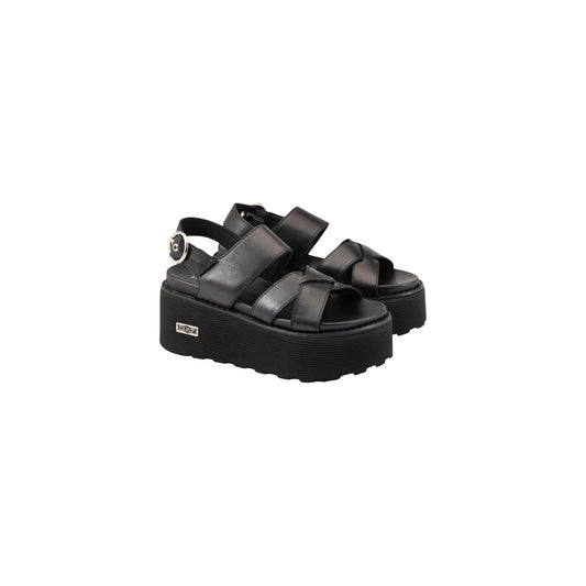 Sandali Platform Cult Nancy; Nero. 100% Pelle, tacco 6 cm. Fasce incrociate, chiusura con fibbia, suola a righe con logo metal. Grintosi, alti e ultra-moderni. Laterale frontale 