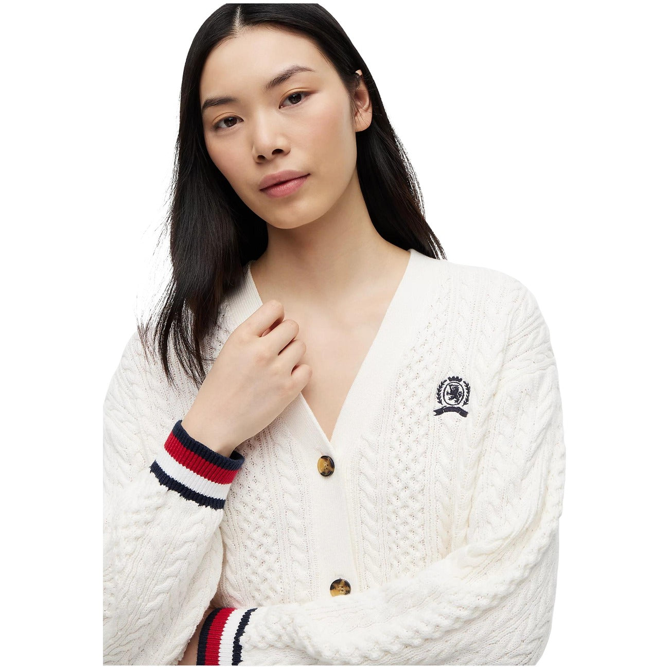 Cardigan Tommy Jeans donna bianco DW0DW22934. Maglione aperto in maglia intrecciata a trecce in 100% cotone biologico, scollo a V con bottoni, vestibilità oversize con stemma logo ricamato e finiture a righe stile college.