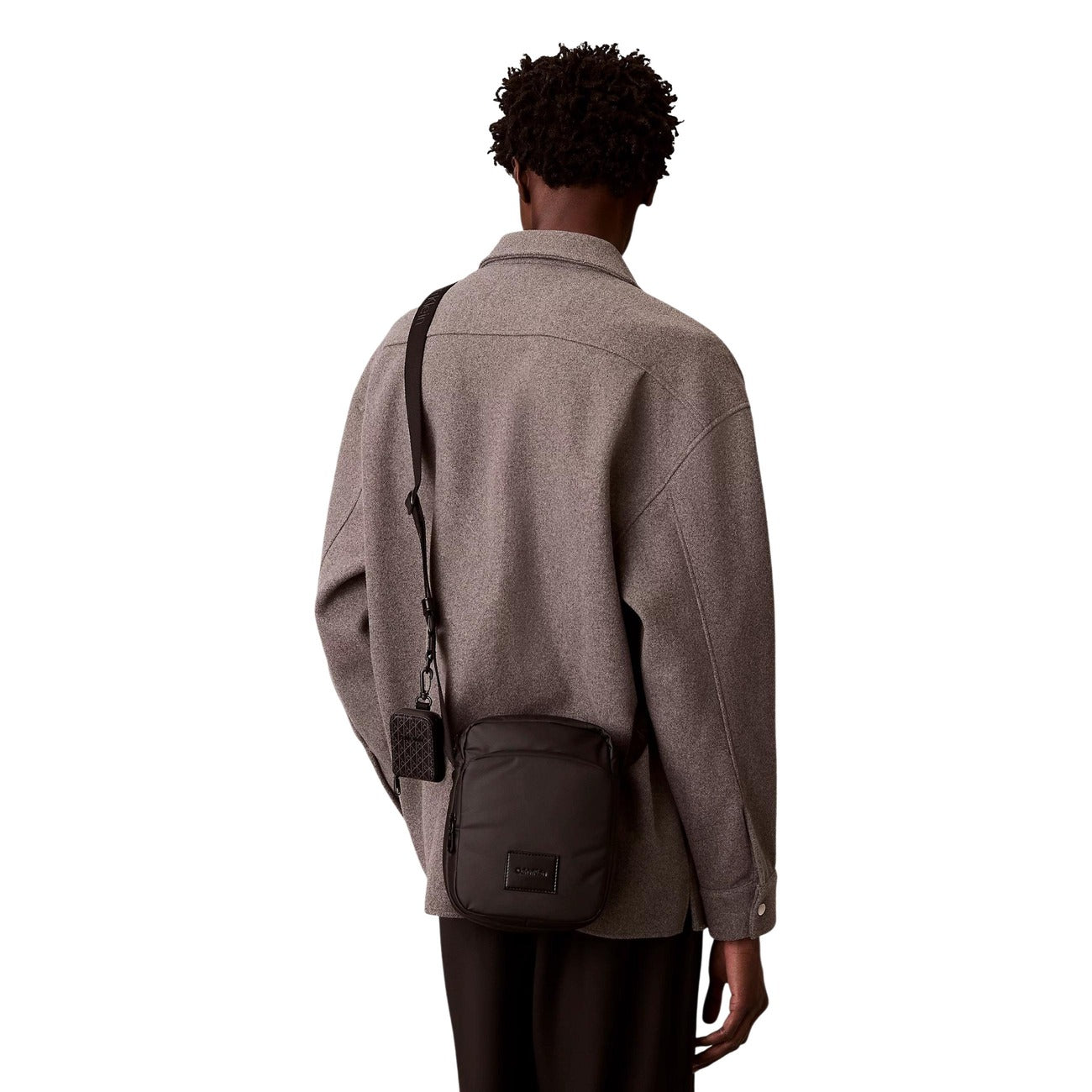 Tracolla uomo Calvin Klein Puffer Utility; 60% Poliestere Riciclato. Design imbottito, tasca frontale zip, logo CK. Borsa reporter compatta, resistente e sostenibile. Indossato da modello 