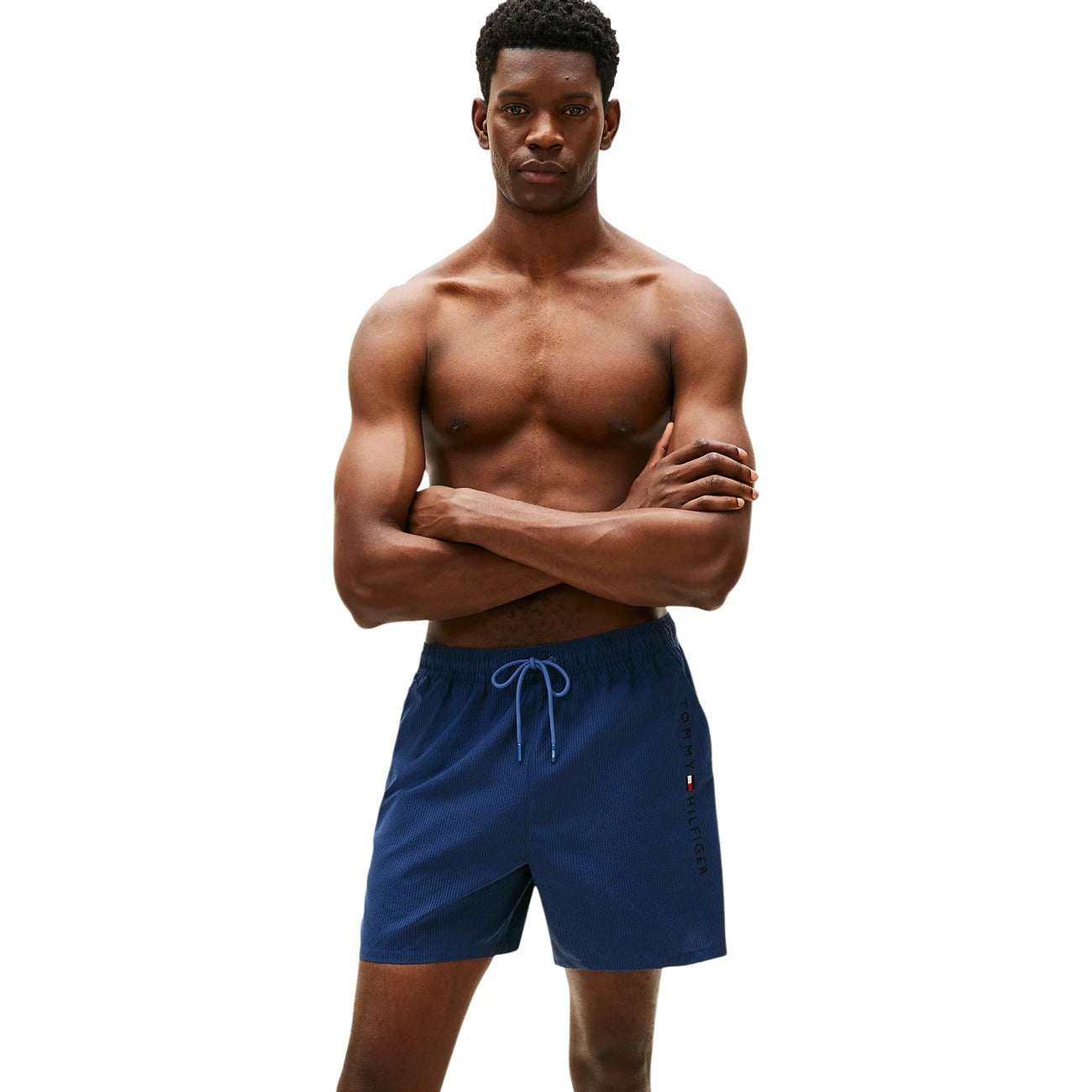 Costume Shorts Tommy Hilfiger; Righe Ithaca tono su tono. Tessuto tecnico, tasca con zip laterale, dettagli iconici sul retro. Lunghezza media, stile nautico elegante e funzionale. Frontale 