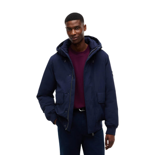 Bomber blu uomo Tommy Jeans DM0DM22032C1G. Giambotto imbottito blu navy antivento e idrorepellente con cappuccio, polsini a coste e patch Tommy.