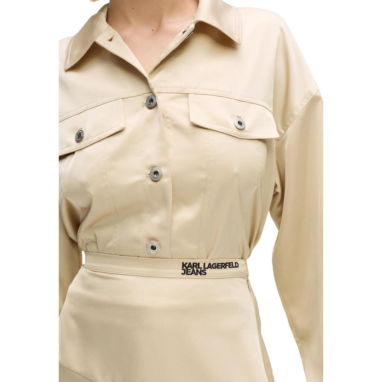 Minigonna Raso Trapezio; 100% Poliestere. Finitura iridescente, zip invisibile, logo ricamato. Gonna corta donna elegante e luminosa per la stagione PE26. Colore beige vista frontale Dettaglio logo 