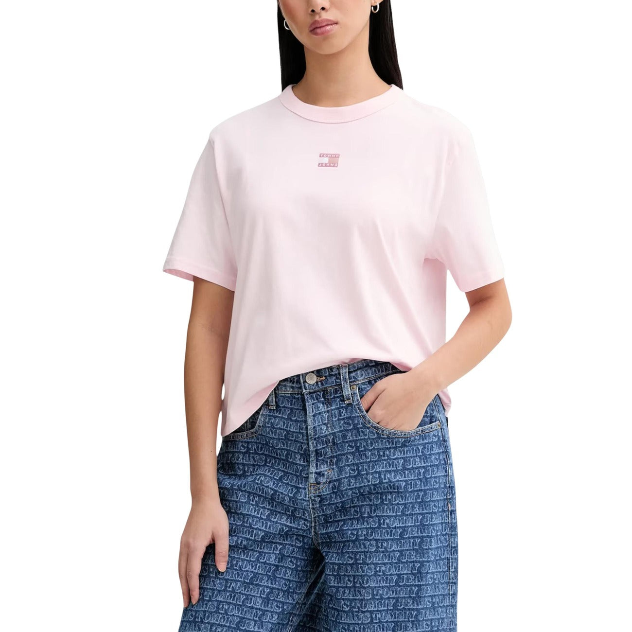 T-shirt Donna Tommy Jeans Boxy Cropped; 100% Cotone. Spalle scese, logo badge sul petto, taglio corto. Maglia donna fresca e di tendenza per la PE26. Colore rosa. Vista frontale 