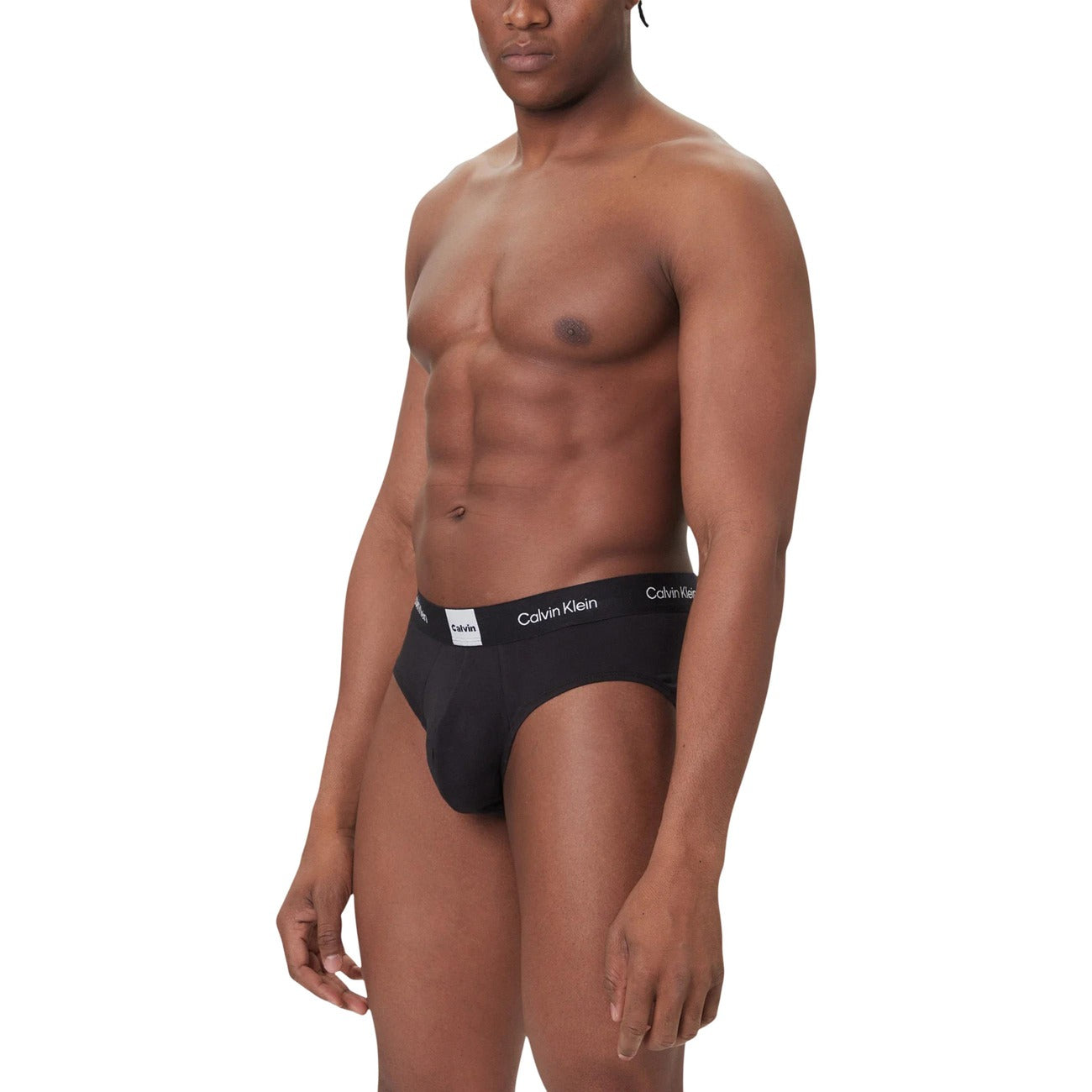 Slip uomo Calvin Klein 3-Pack; 95% Cotone Better Cotton, 5% Elastan. Modello Hip Brief con elastico logato. Intimo uomo resistente, elastico e iconico. Indossato da modello 