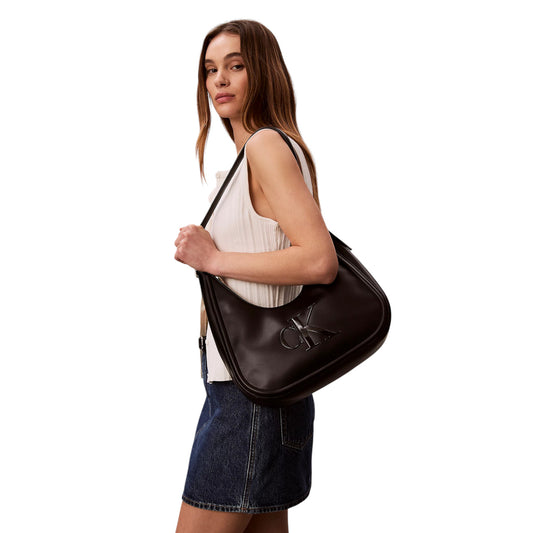 Borsa Mezzaluna Calvin Klein Bold; Nero. 100% Poliuretano morbido, stile hobo a spalla, chiusura zippata, logo CK in rilievo. Dimensioni medie (33 cm), design iconico e versatile 4 stagioni. Indossata da modella 
