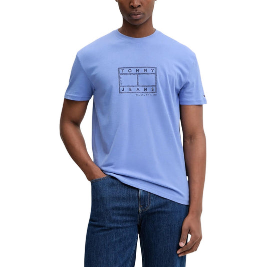 T-shirt Tommy Jeans Azzurra; 100% Cotone Rigenerato. Regular fit, stampa grafica frontale, girocollo a costine. Stile casual sostenibile, ideale per la stagione calda e il tempo libero. Vista frontale 