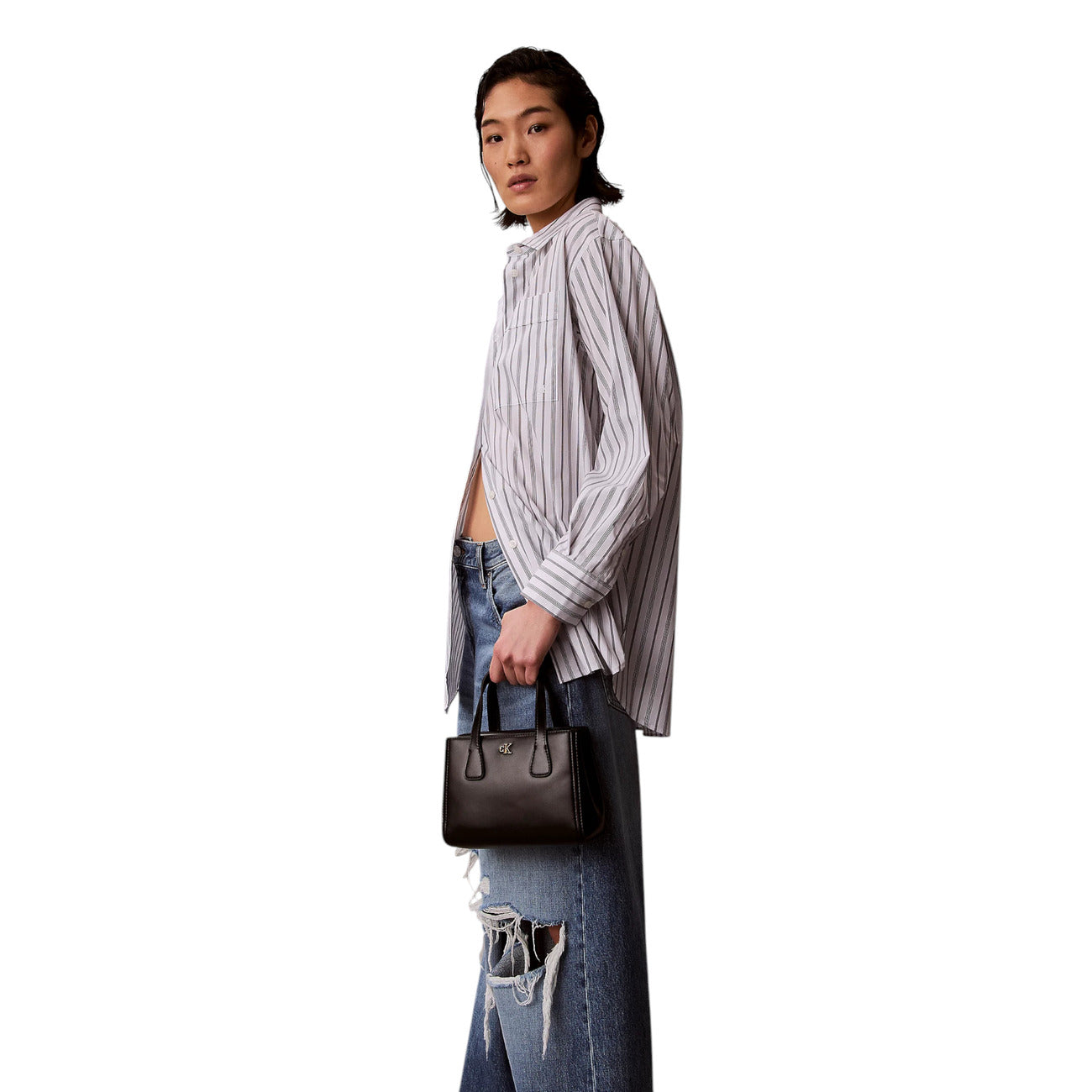 Borsa Mini Tote Calvin Klein Crossbody; Nero. 51% Poliestere riciclato a struttura rigida, chiusura zippata, doppi manici e tracolla removibile. Tasca interna. Misure micro e compatte (20x14 cm), stile minimalista. Indossata da modella 