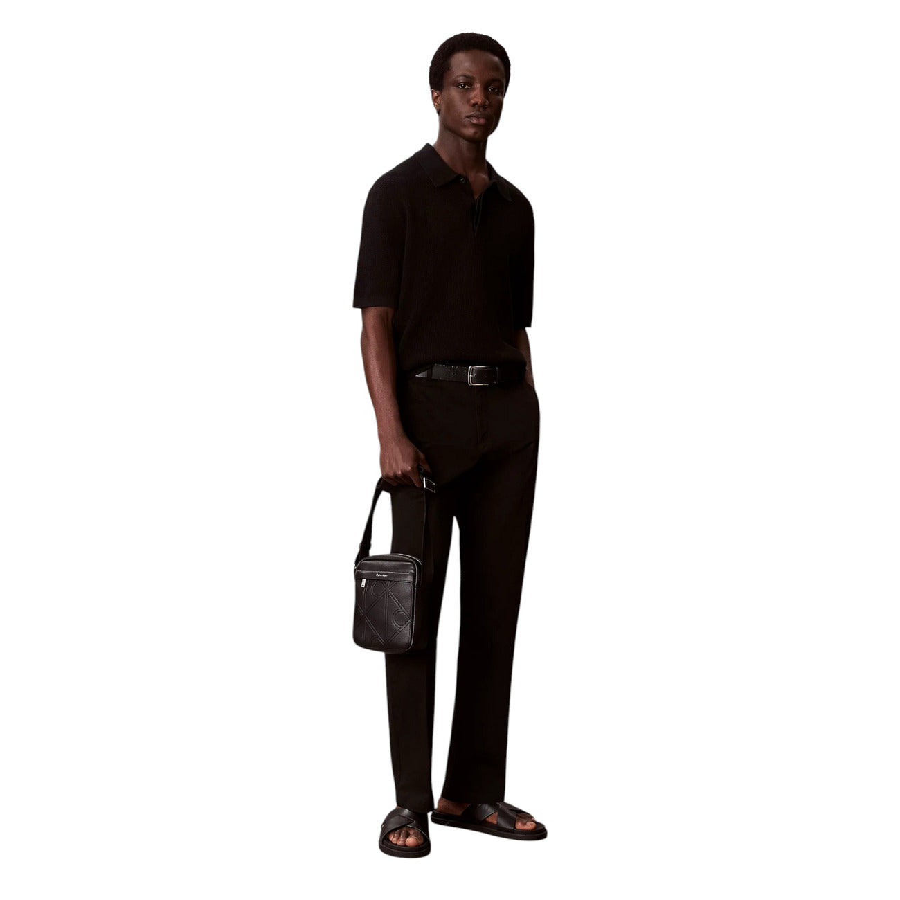 Borsa Tracolla Uomo Calvin Klein Reporter; Nero. 100% Poliuretano effetto pelle martellata con loghi incisi, chiusura zippata, tracolla regolabile. Dimensioni compatte (16x20 cm), stile minimal e moderno 4 stagioni. Indossato da modello 