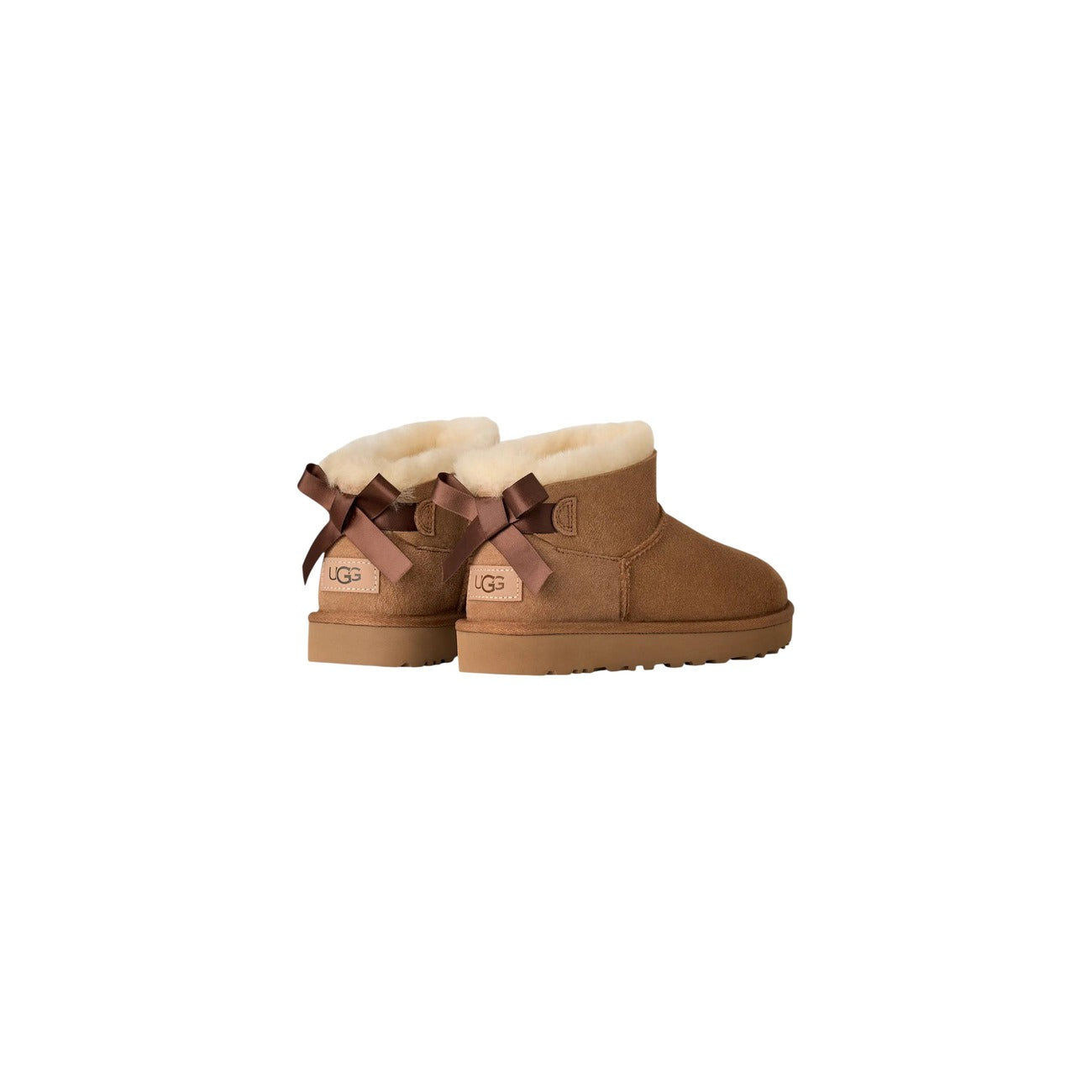 UGG Ultra Mini Bailey Bow donna Chestnut 1185491. Stivaletti bassi in pelle scamosciata beige foderati in caldo montone con fiocco in raso posteriore, suola leggera in EVA e trattamento idrorepellente.