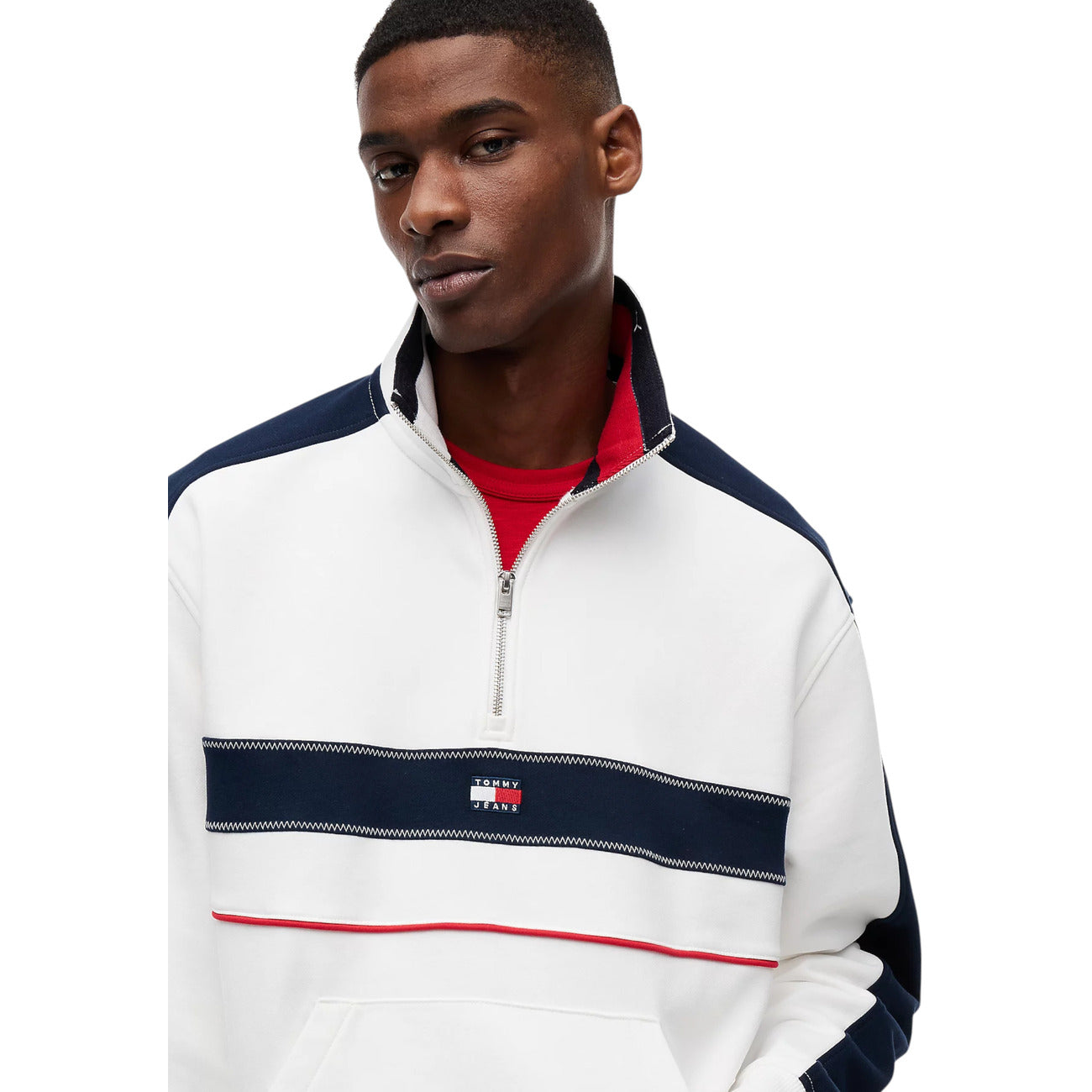 Felpa Uomo Tommy Jeans; Bianco e Multicolore. Tessuto in spugna di cotone organico, taglio relaxed fit con spalle scese, collo a imbuto con mezza zip e tasca a marsupio. Logo badge frontale, stile street-wear 4 stagioni. Dettaglio 