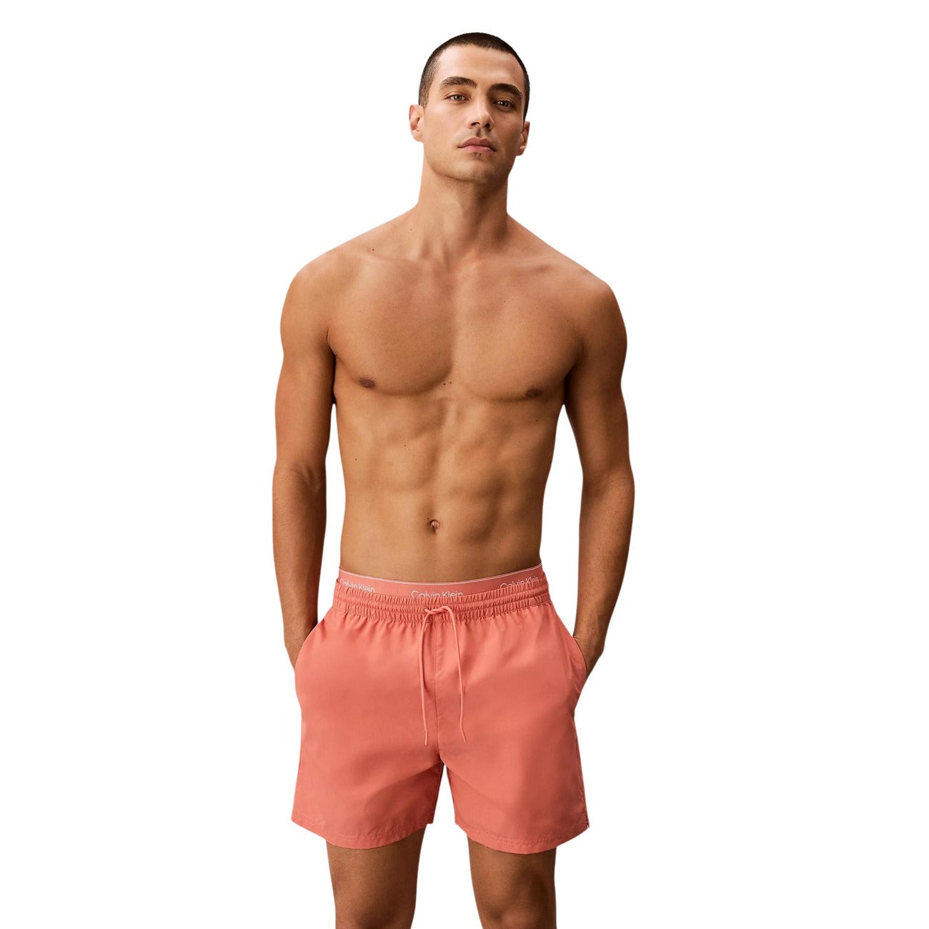 Boxer Mare CK Essentials; Tessuto Impermeabile. Doppia vita elastica logata, asciugatura rapida, lunghezza media. Tasca con velcro, slip a rete interno. Stile minimalista e funzionale per l'estate. Arancione albicocca 