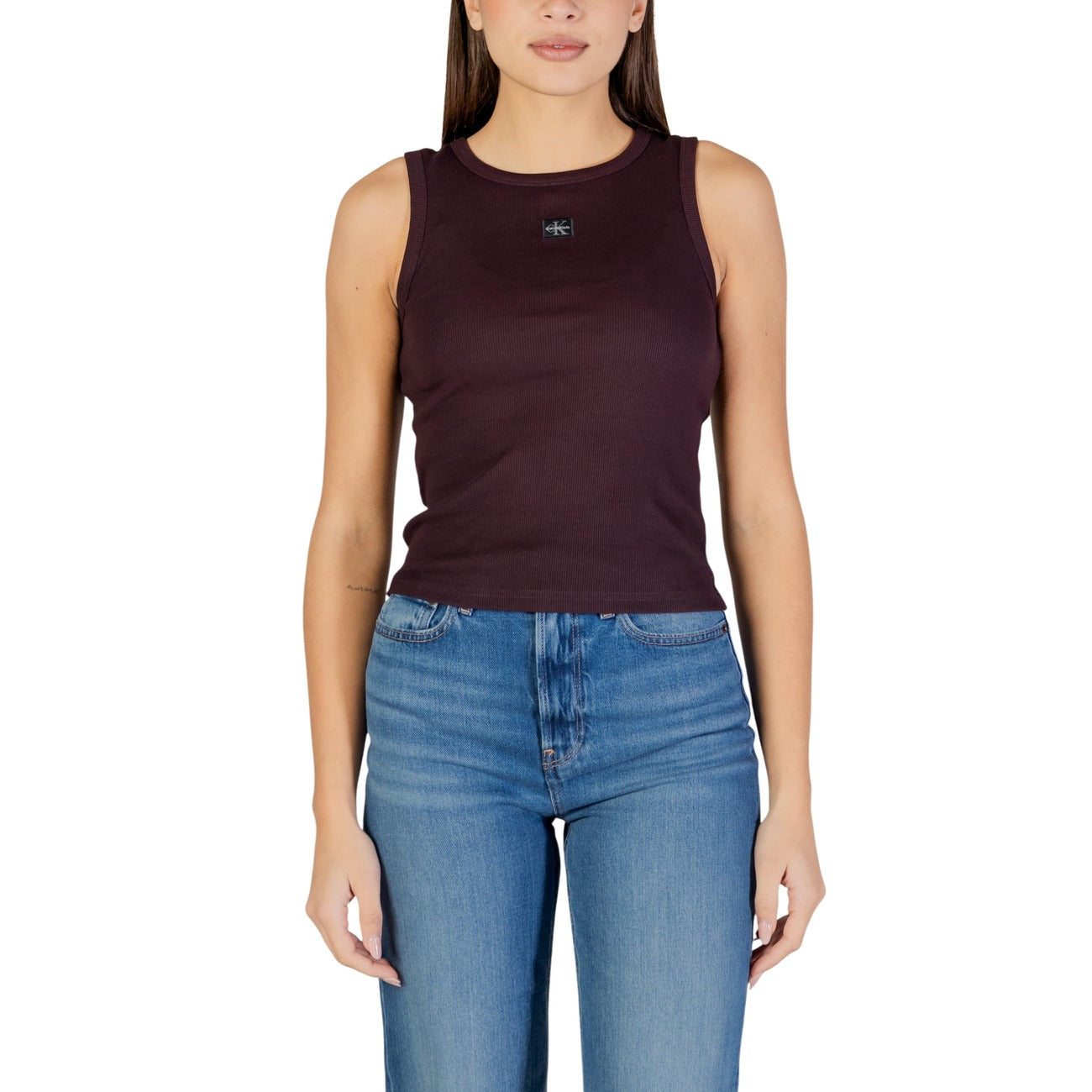 Canotta CK Jeans Woven Label; 95% Cotone, 5% Elastane. Lavorazione a costine 2x2, vestibilità aderente, logo etichetta tessuta. Top donna estivo fresco, elastico e di tendenza. Colore marrone vista frontale Indossata da modella 