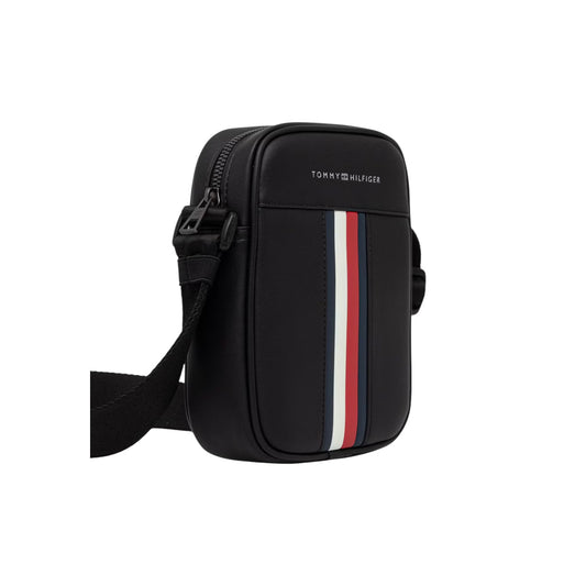 Borsa Reporter Uomo Tommy Hilfiger TH Metro; Nero. 100% Poliuretano liscio, chiusura superiore con zip, tracolla regolabile e nastro iconico frontale. Misure verticali e compatte (15x20 cm), capienza 1,85 litri. Frontale laterale 