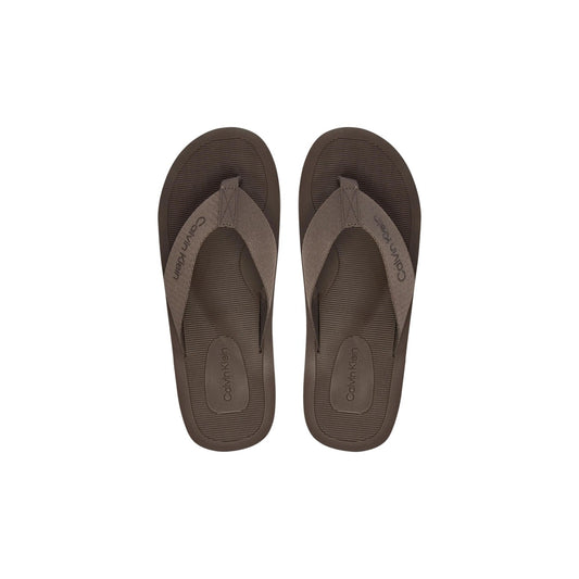 Infradito Calvin Klein HM0HM02106; 100% Poliestere. Doppia stampa logo, suola grip, fascia ampia. Ciabatte uomo mare e piscina, leggere e resistenti per la PE26. Colore marrone vista frontale 