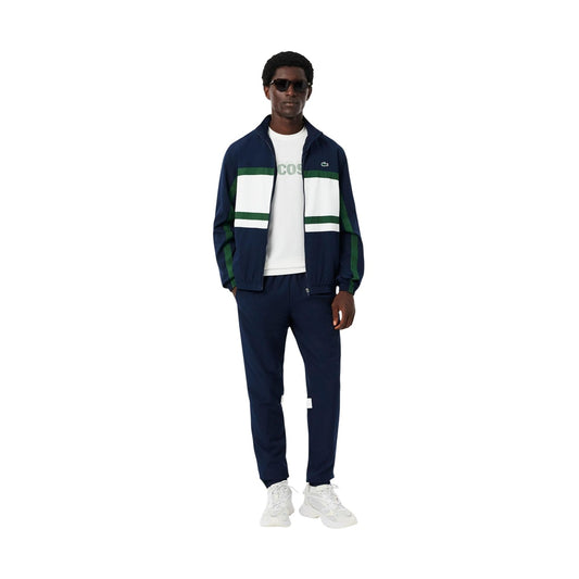 Lacoste Tennis Tracksuit Navy/White; 100% poliestere, resistente all'acqua, fondo gamba con zip. La tuta da tennis professionale classica e traspirante. Vista frontale 